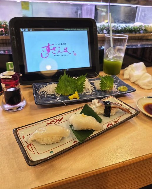 A tray of sashimi and a tablet menu at a Tsukiji restaurant counter