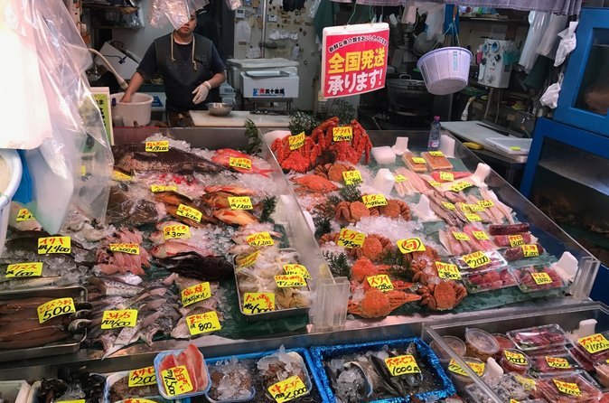 Packed seafood in a chilled Tsukiji case, each tray under a hand-written price tag