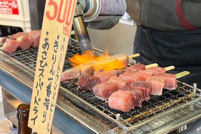 Sake poured over tuna skewers grilling at a Tsukiji stall