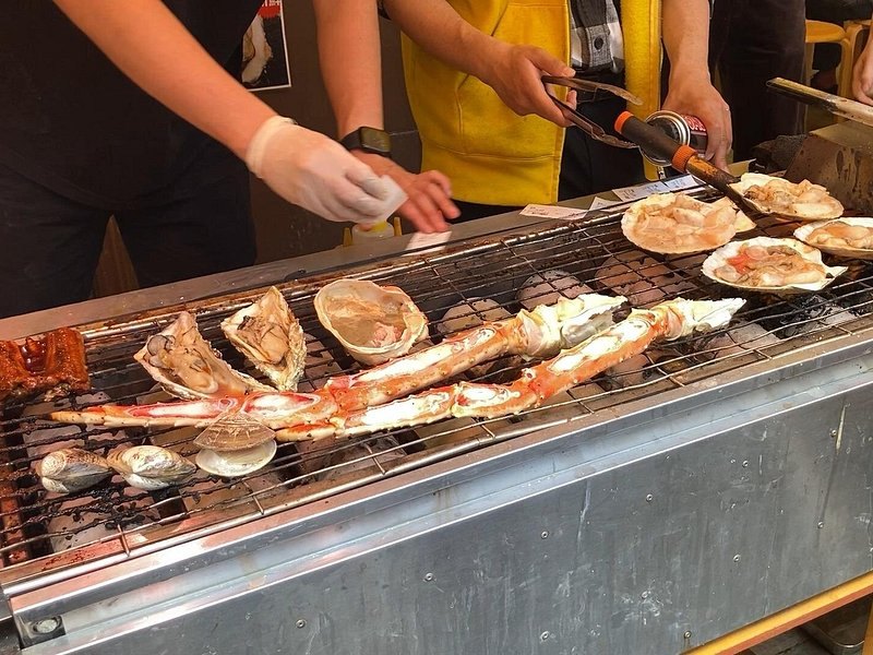 Scallops and crab legs cooking on a griddle at a Tsukiji street stall