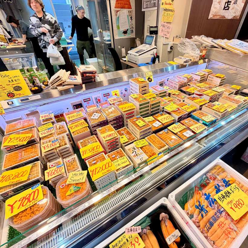 A Tsukiji stall case packed with boxes of salmon roe and sea urchin under yellow price tags